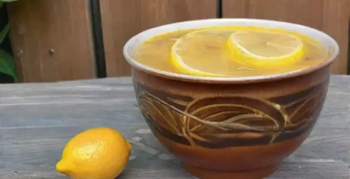 Una taza de café humeante con limones cortados descansa sobre una mesa rústica
